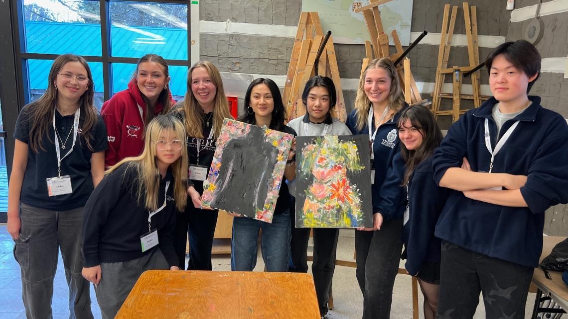 Group of students holding two pieces of artwork