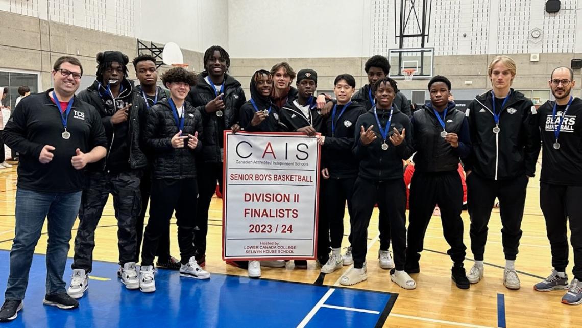 Group of basketball players in sweatsuits holding a banner