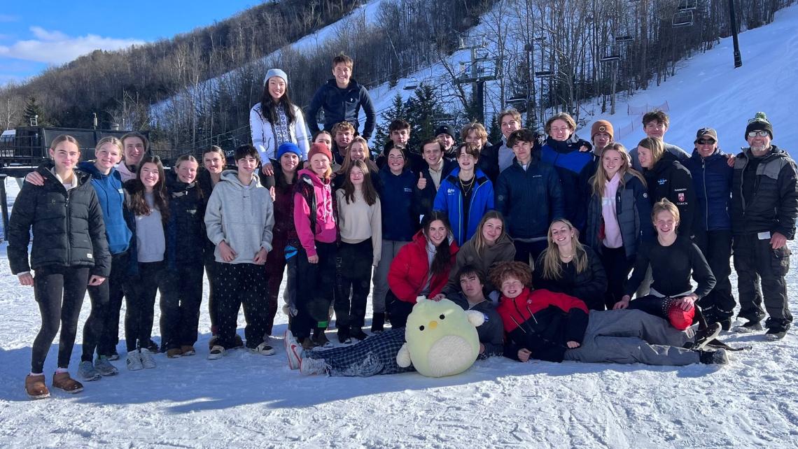 Group of students in winter clothing standing in front of ski hills