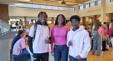 Three students wearing pink shirts