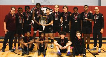 Basketball team, each wearing medals, poses on court with plaque