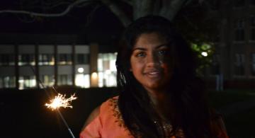 Student in traditional Indian dress holding sparkler