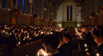 Darkened Chapel Filled with People Holding Lit Tapers